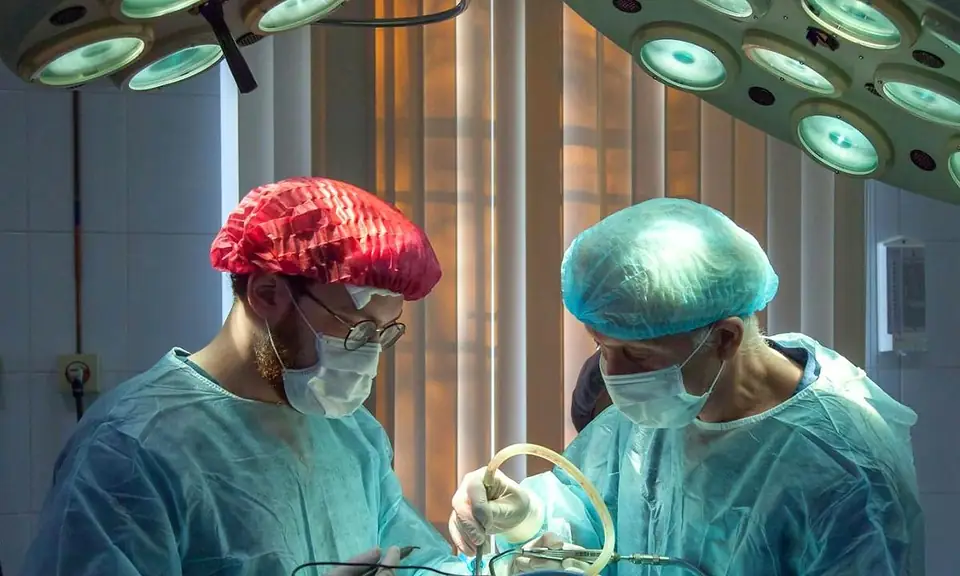 Two surgeons operating under theatre lights
